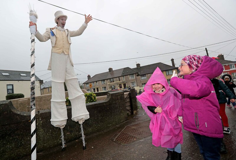 Despite the rain, Jack Frosty (Will Flanagan of Alchemy Arts)  greets, Jodie Peyton O'Brien and Lily Mae O'Sullivan, both Senior Infants, as they walk on Cathedral Road.
EEjob 17/12/2020
Echo News.
Holly Jolly walk with Jack Frosty on stilts, at St. Vincent's Convent Primary School, Cork.
Picture: Jim Coughlan.